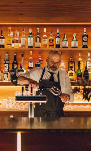 Hotel & Villa Auersperg Barkeeper an der Bar schenkt Rotwein ein